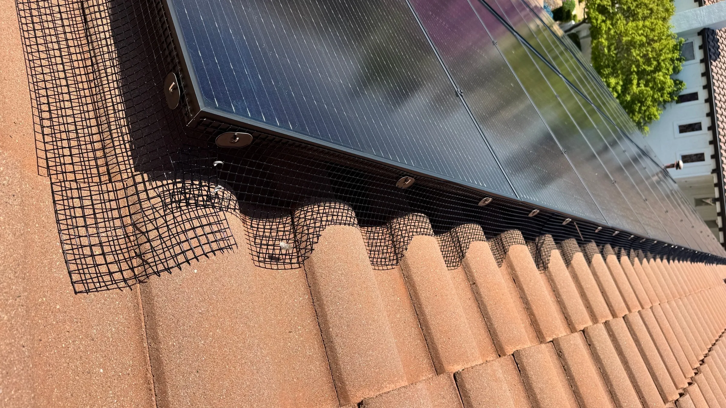 Solar panel bird proofing in Fresno, CA — Golden Rays critter guard mesh fastened along the edge of a rooftop solar array on a tile roof